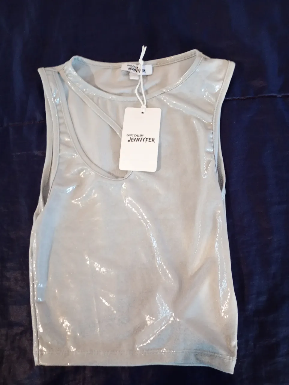 Top de mujer, musculosa con diseño asimétrico y detalle en el cuello. Ideal para un look moderno y sofisticado.