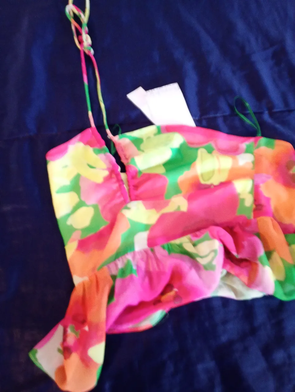 Top de mujer con estampado floral en tonos rosa, amarillo y verde. Con tirantes finos y detalle de volados. Ideal para un look fresco y veraniego.