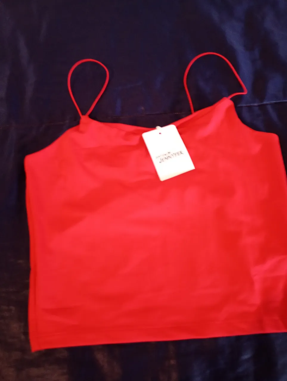 Top rojo con tirantes finos y etiqueta de la marca. Ideal para un look fresco y moderno.