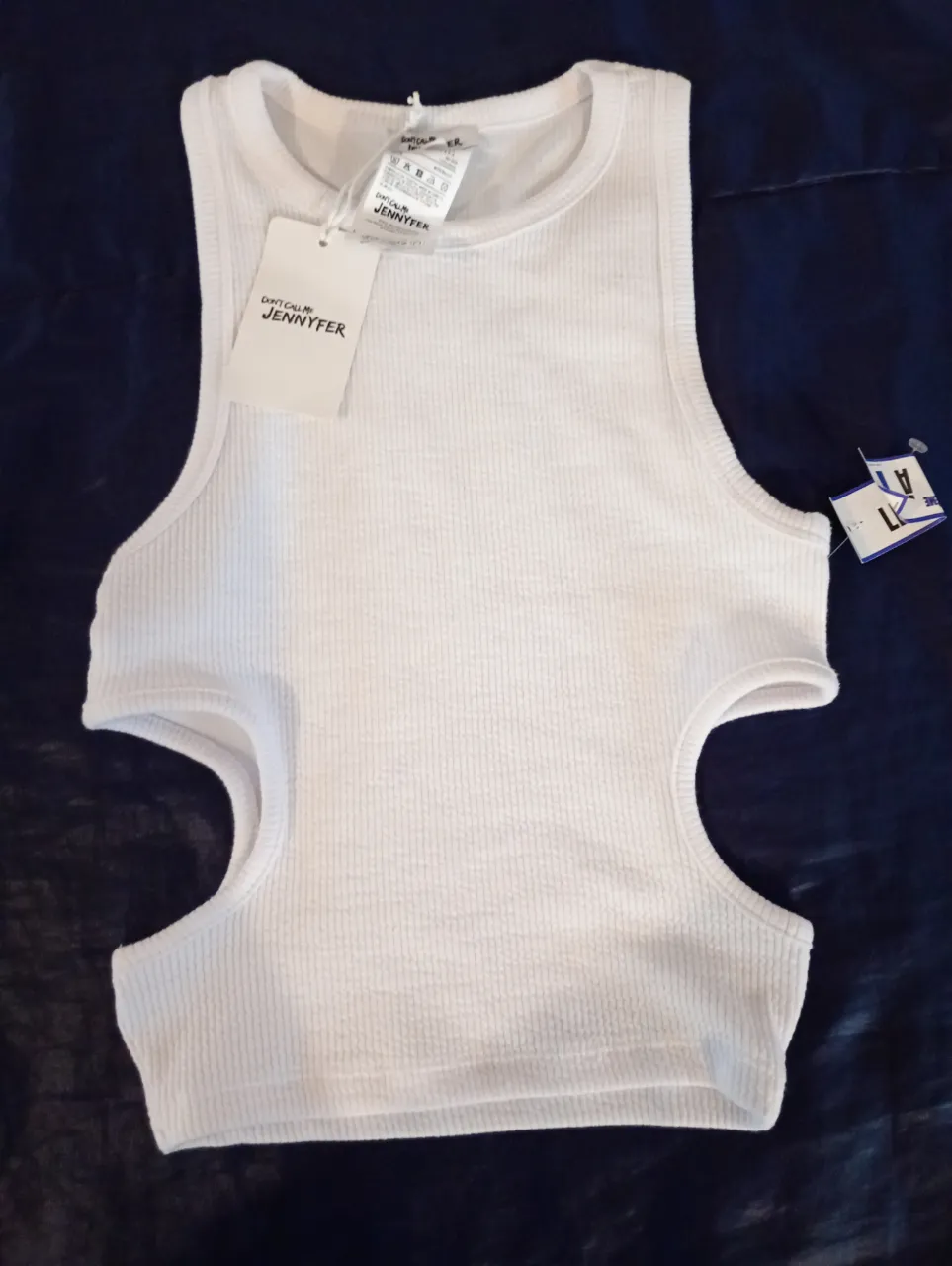 Top blanco con cortes laterales, ideal para un look moderno y fresco. Perfecto para combinar con jeans o shorts.