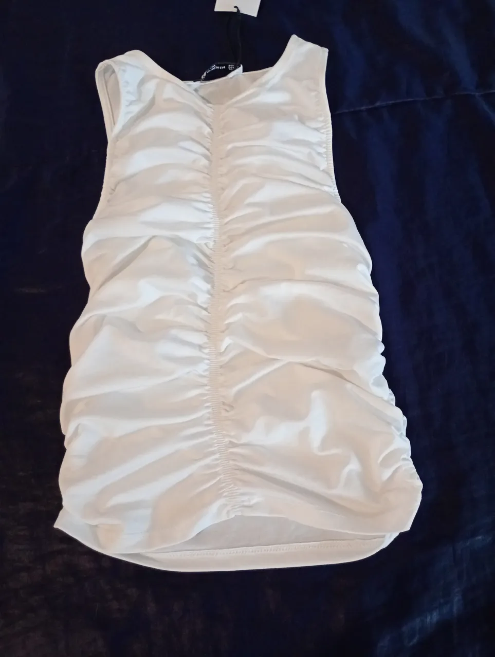 Vestido mini blanco con frunces en el frente, ideal para una salida casual o una fiesta. Diseño ajustado y moderno.