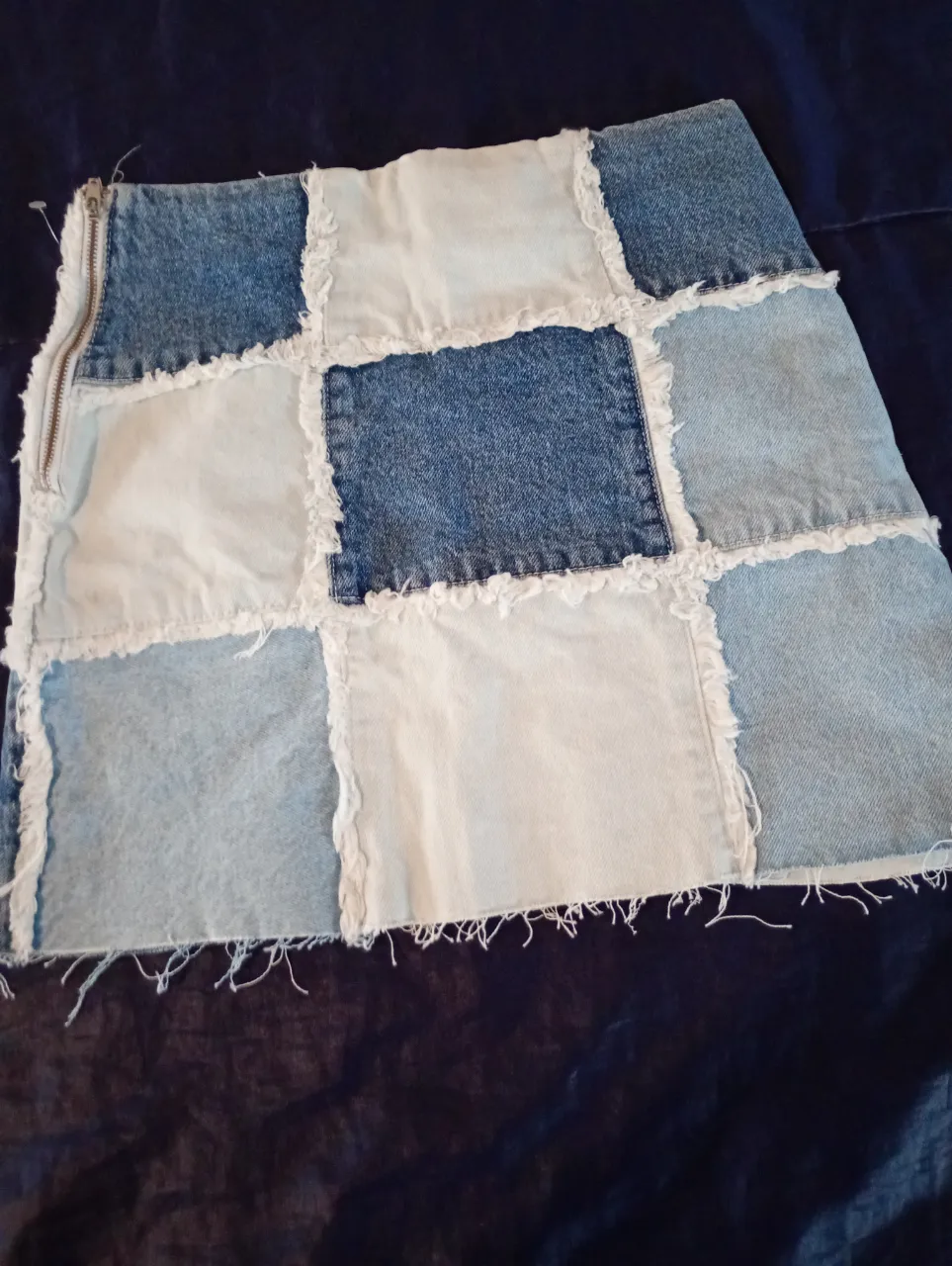 Pollera larga patchwork de jean, con parches en diferentes tonos de azul y blanco. Diseño artesanal con bordes deshilachados y cierre lateral.