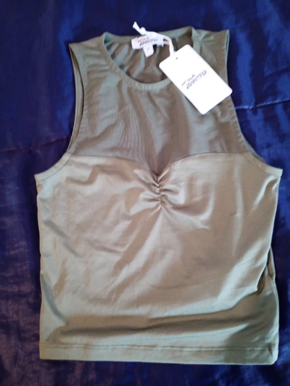 Top deportivo verde con detalle fruncido en el busto y espalda descubierta. Ideal para entrenamientos de alto impacto.