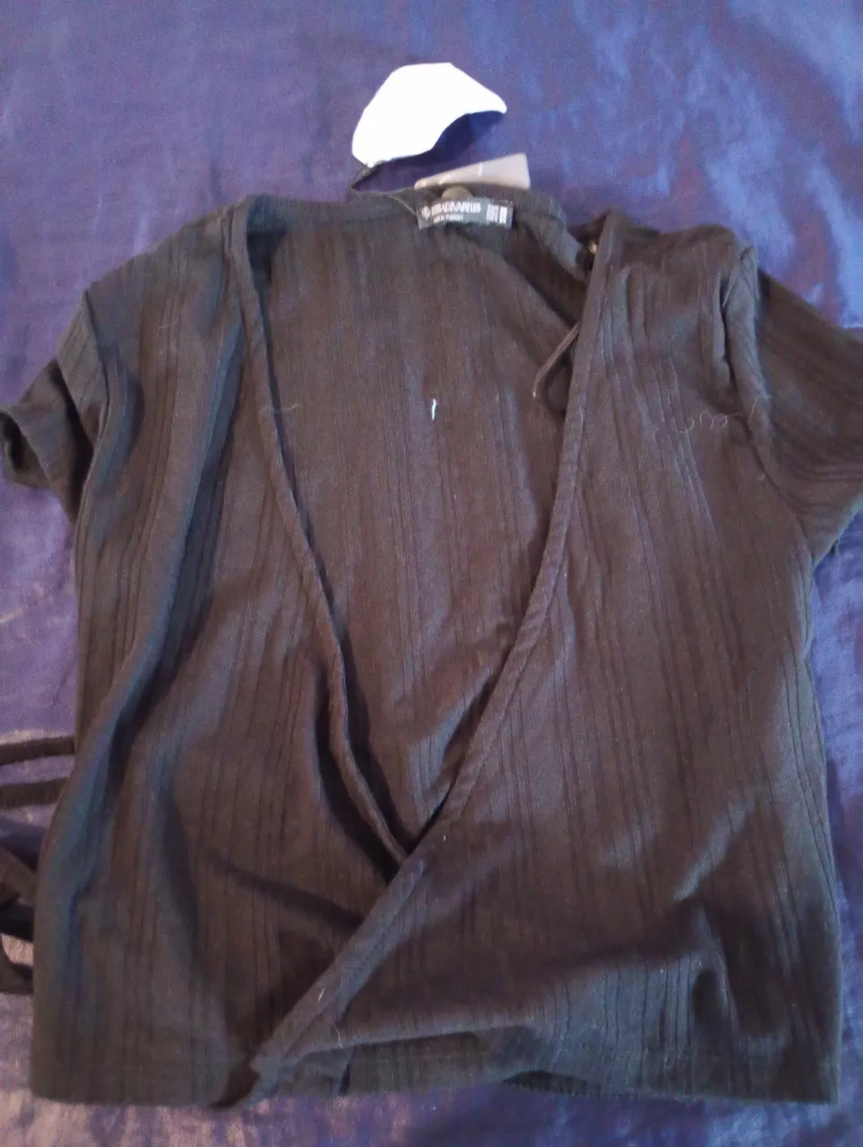 Top negro de mujer, con diseño cruzado y mangas cortas. Ideal para un look moderno y versátil.