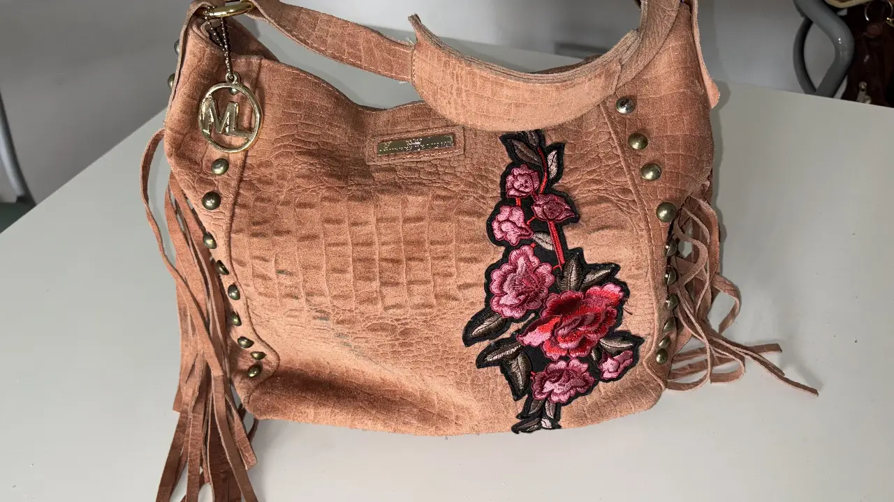 Cartera de hombro estilo boho, confeccionada en gamuza con detalles de bordado floral y flecos. Ideal para un look casual y con onda.