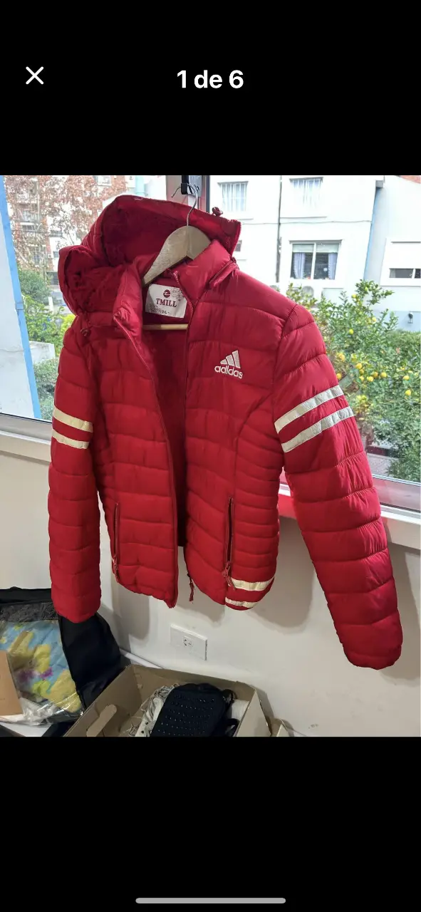 Campera roja acolchada con capucha y forro interior de piel. Tiene el logo de Adidas y detalles en blanco en las mangas. Ideal para el invierno.