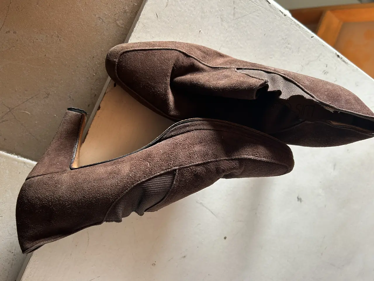 Elegantes zapatos de taco alto en gamuza marrón, ideales para ocasiones especiales. Diseño clásico con detalles de ajuste elástico para mayor comodidad.