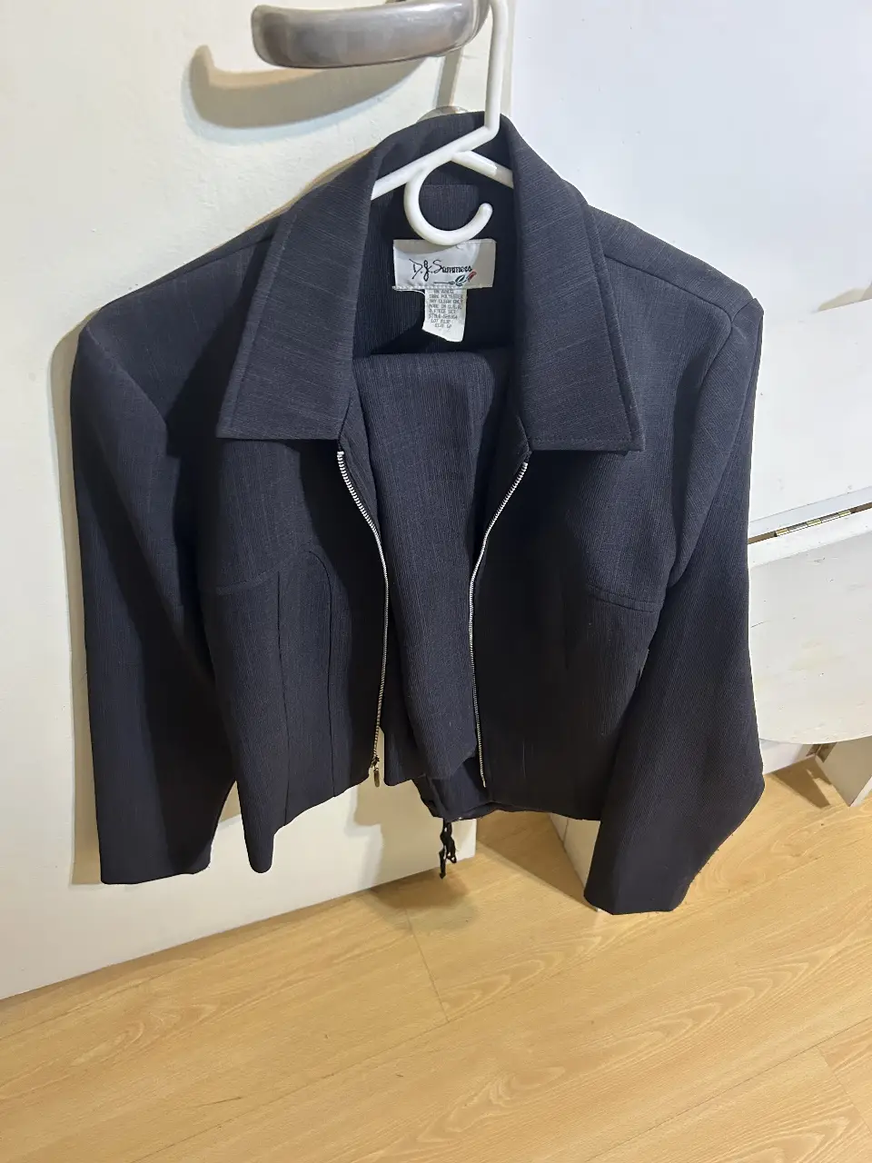 Traje de dos piezas de mujer, ideal para el trabajo o eventos formales. Incluye un blazer con cierre y solapas, y un pantalón sastrero a juego. Confeccionado en un tejido de color negro.