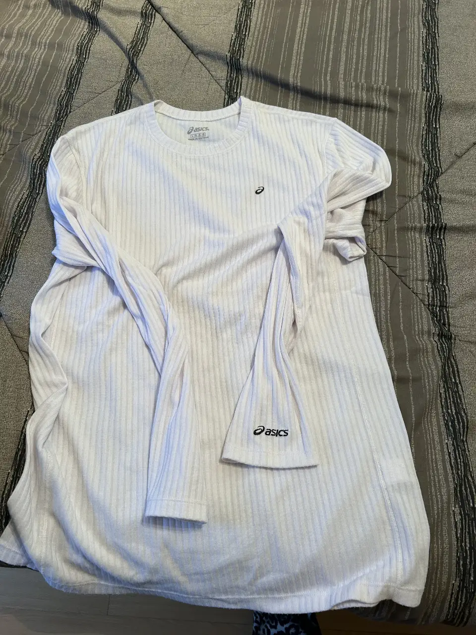 Remera manga larga blanca de hombre, con cuello redondo y logo de Asics en el pecho y manga. Ideal para entrenamientos o uso casual.
