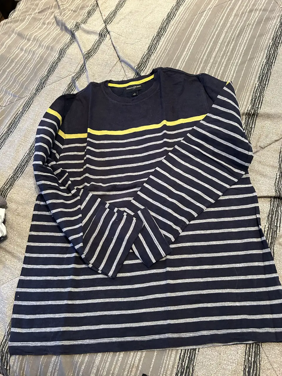 Remera manga larga de hombre, a rayas horizontales en azul marino y blanco. Detalles en amarillo en el cuello y una franja horizontal en el pecho. Marca Banana Republic, ideal para un look casual y cómodo.