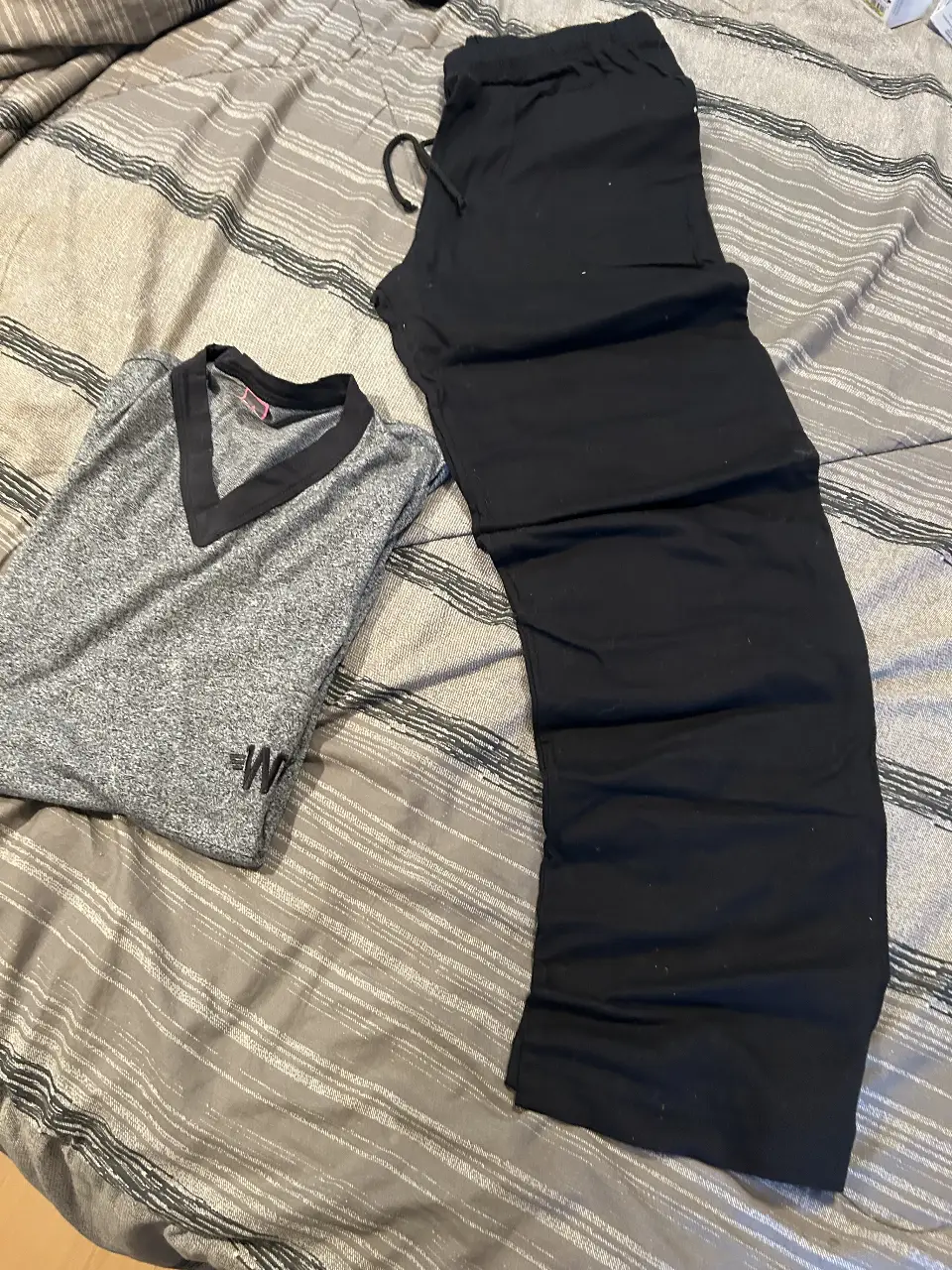 pijama de hombre, incluye pantalón negro con cintura elastizada y remera gris con cuello en V y detalle de bolsillo con logo.