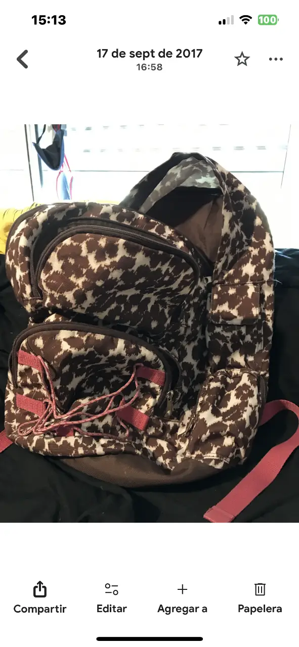 Mochila con estampado de manchas marrones y blancas. Cuenta con múltiples bolsillos y correas rosas. Ideal para llevar tus cosas con estilo.