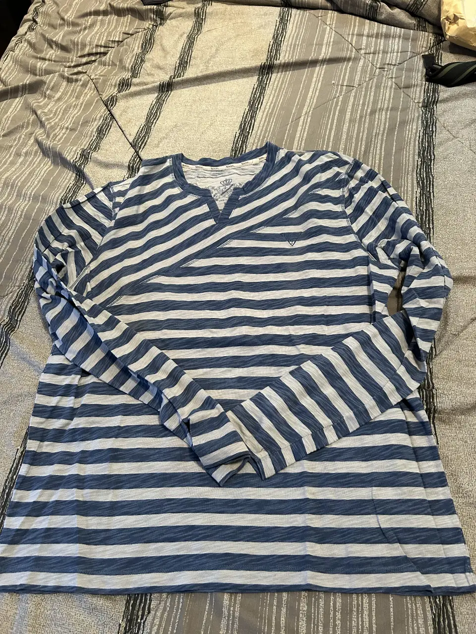 Remera manga larga a rayas azul y blanca de la marca Guess. Cuello en V con detalle de la marca en el frente. Talle L.