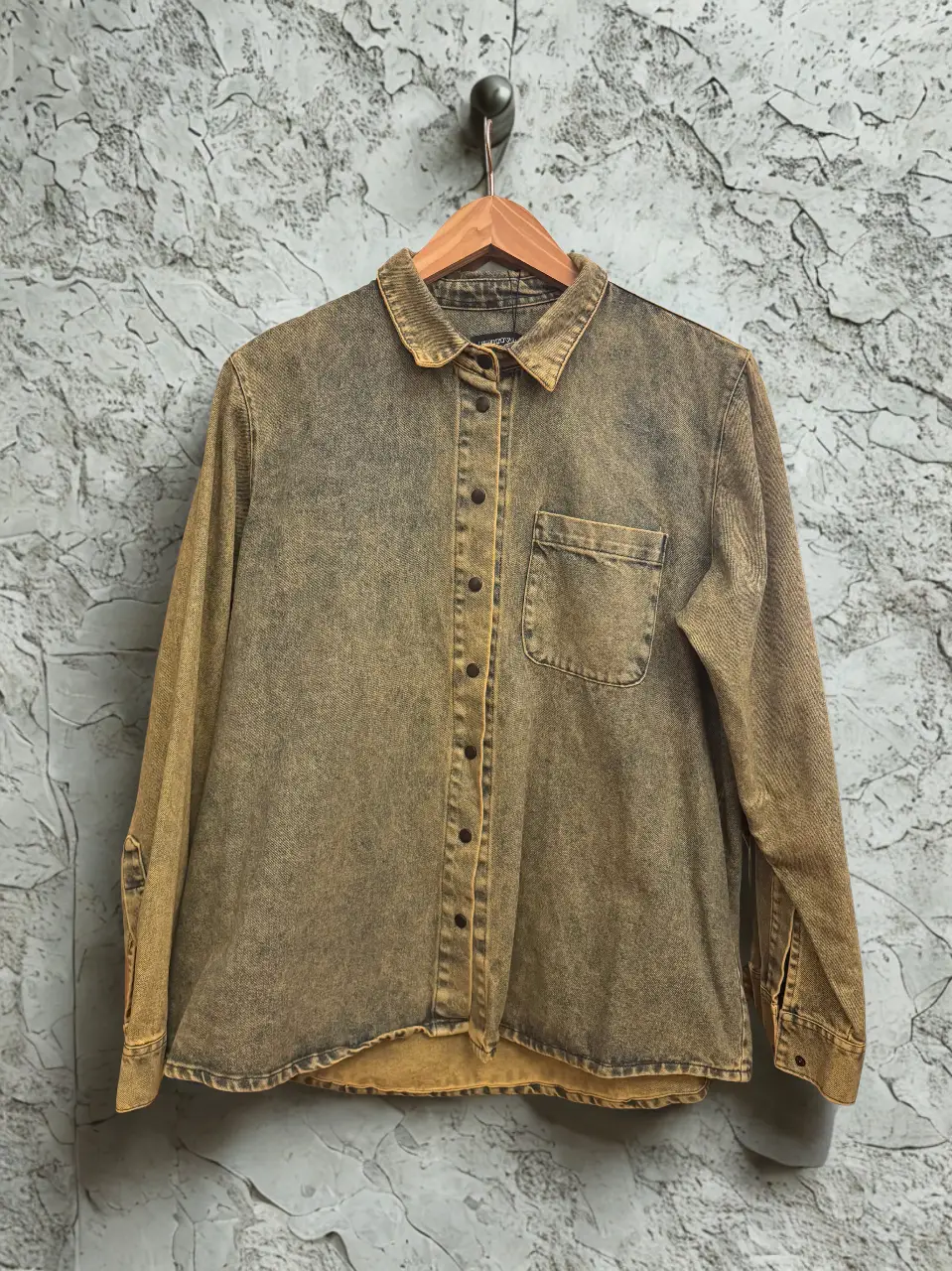 Camisa de jean marca Unitivo Unisex con efecto desgastado en tonos amarronados. Posee un bolsillo en el pecho y botones. Ideal para un look casual y con onda.