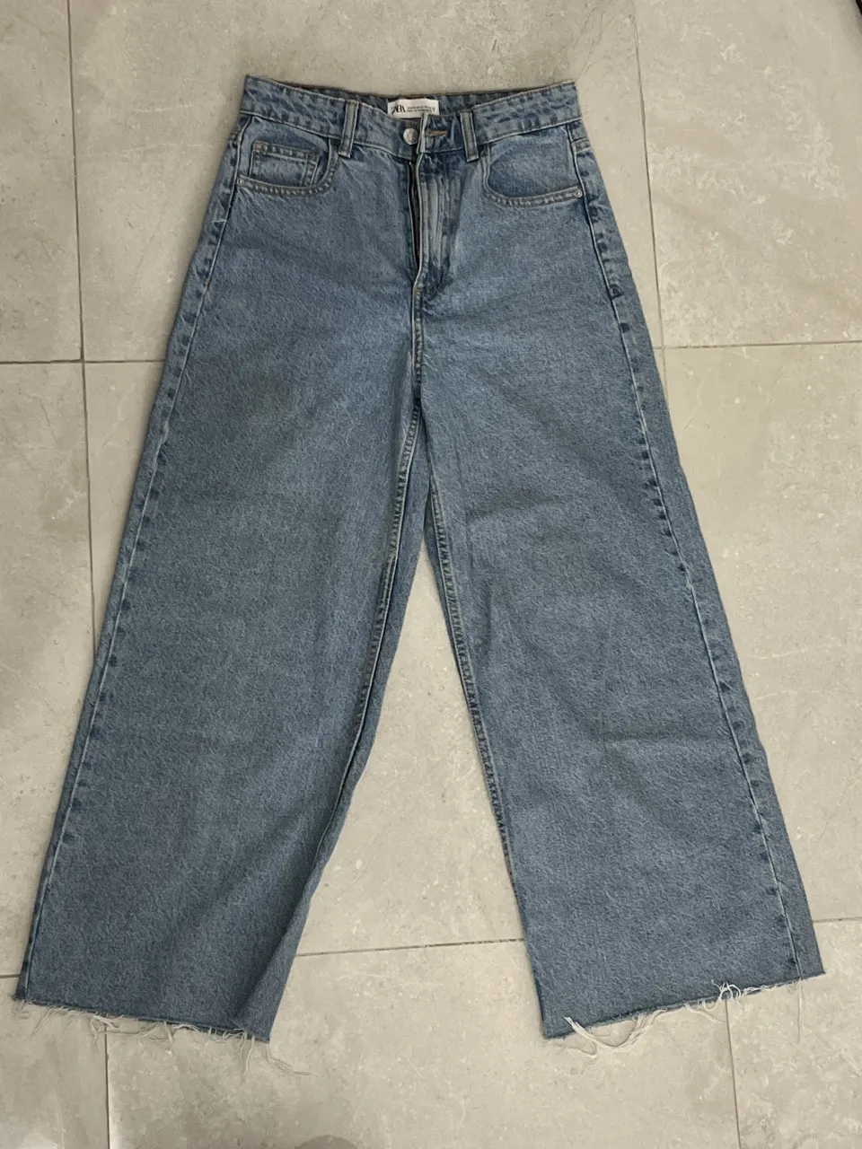 Jeans tiro alto y desflecado en los bajos. manchita en la pierna