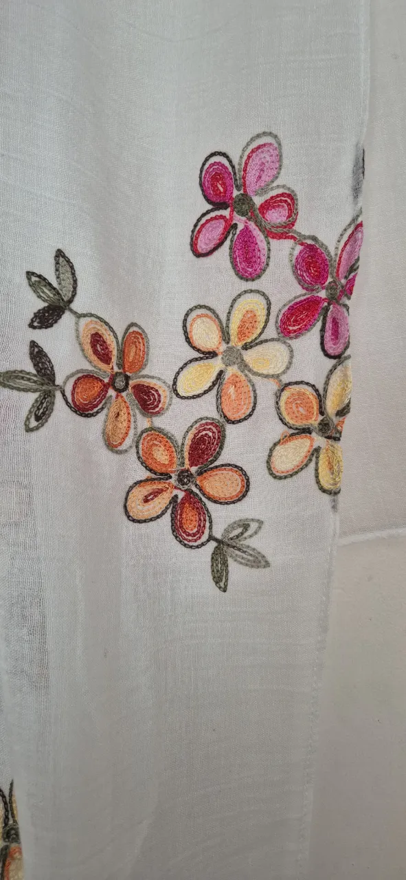 Pañuelo blanco con bordado de flores en tonos rosas, naranjas y amarillos. Ideal para darle un toque de color a tu outfit.