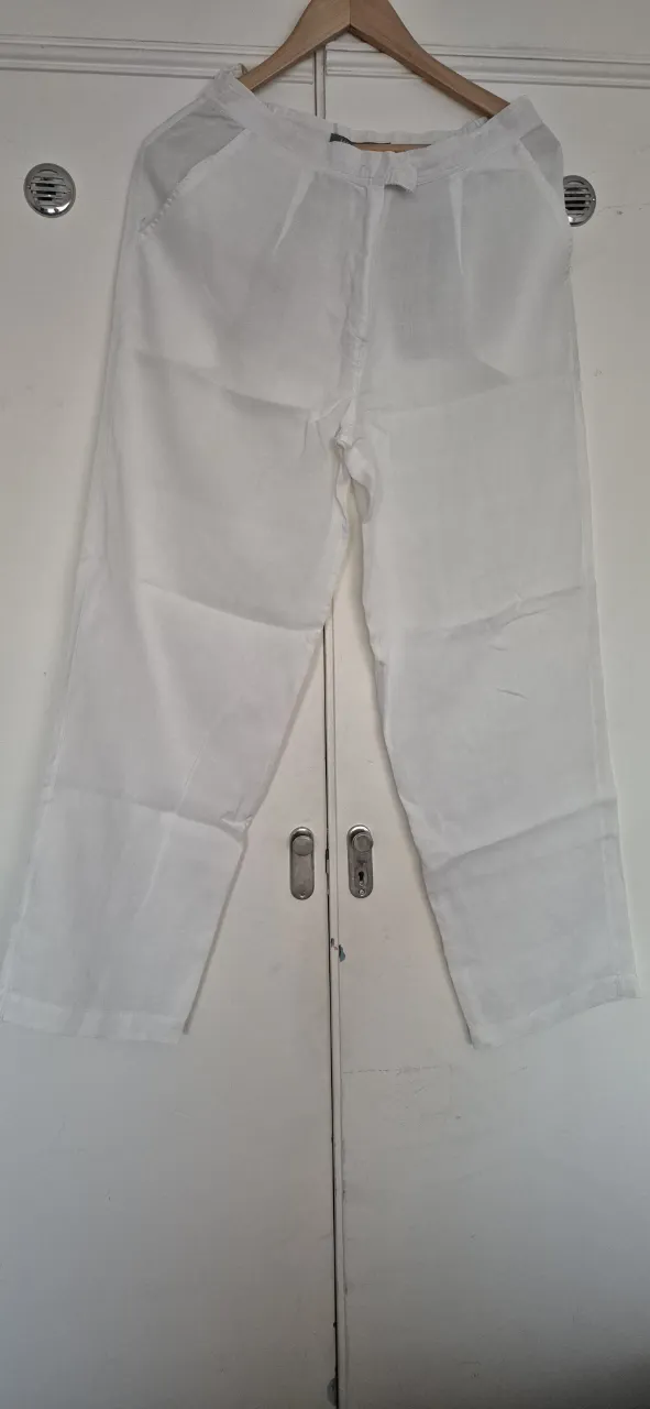 Pantalón blanco de lino, tiro alto, con bolsillos. Ideal para un look fresco y cómodo.