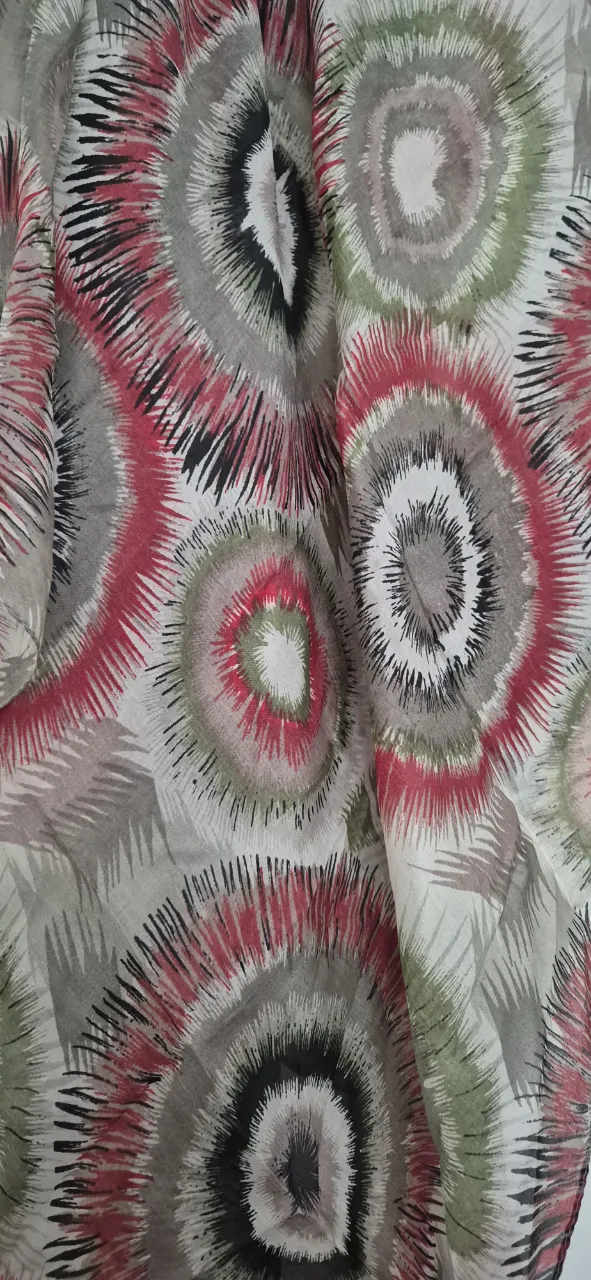Pañuelo estampado con diseño abstracto de círculos concéntricos en tonos rojos, verdes, grises y negros. Ideal para complementar cualquier outfit y darle un toque de color y estilo.