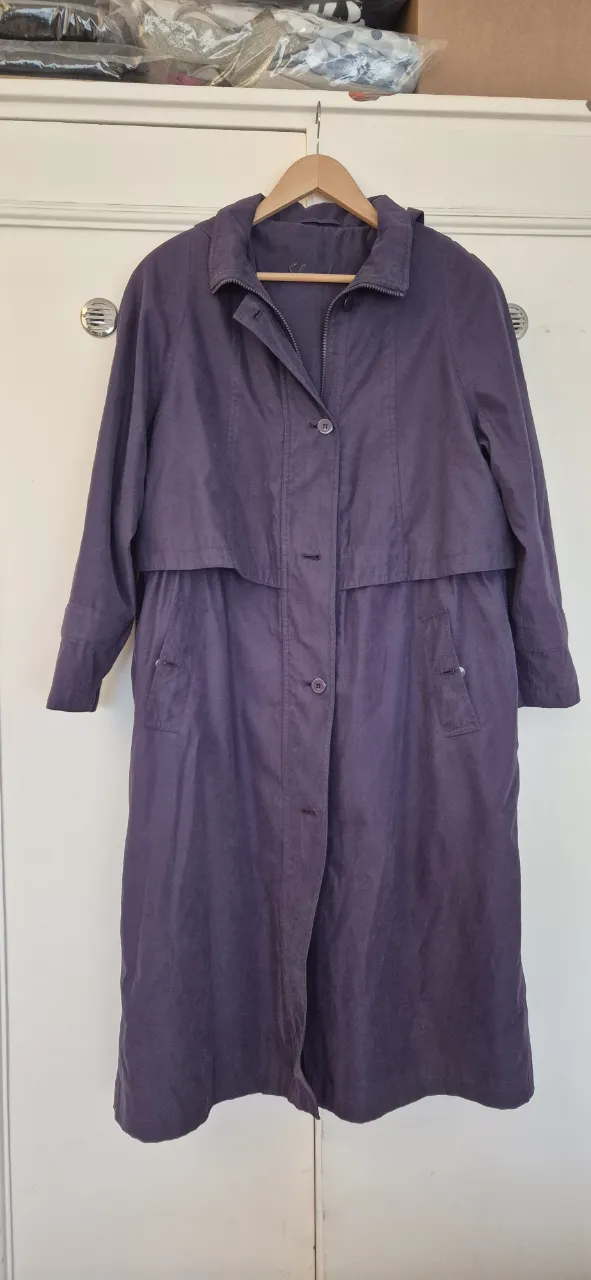 Piloto de lluvia largo de color violeta, ideal para días frescos. Posee capucha desmontable, cierre y botones al frente, y bolsillos laterales.Es forrado, con bolsillo interno . Un clásico que no puede faltar en tu guardarropa.