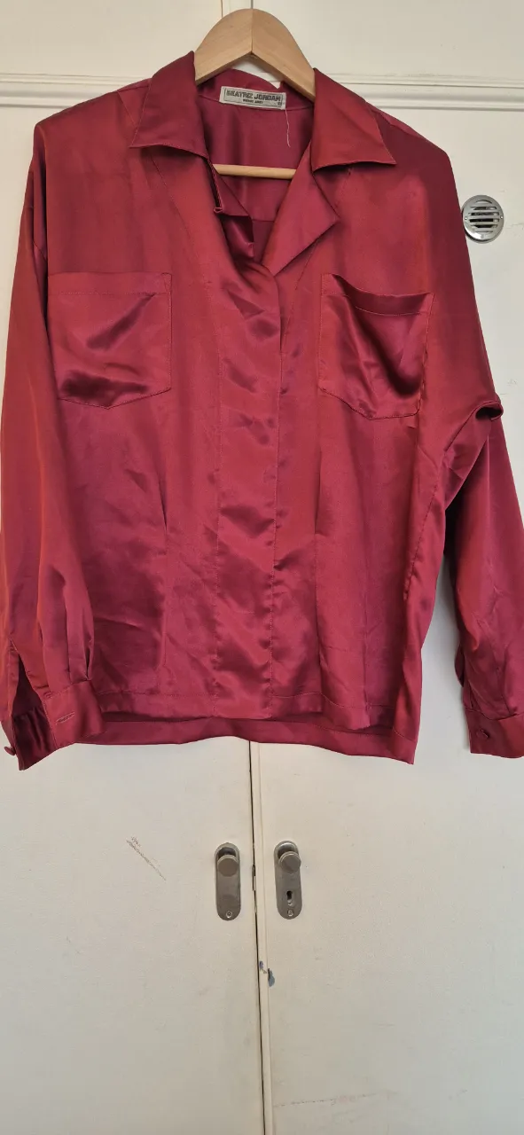 Camisa de seda color bordó, con dos bolsillos en el frente y mangas largas con puño y botón. Ideal para un look elegante y sofisticado.