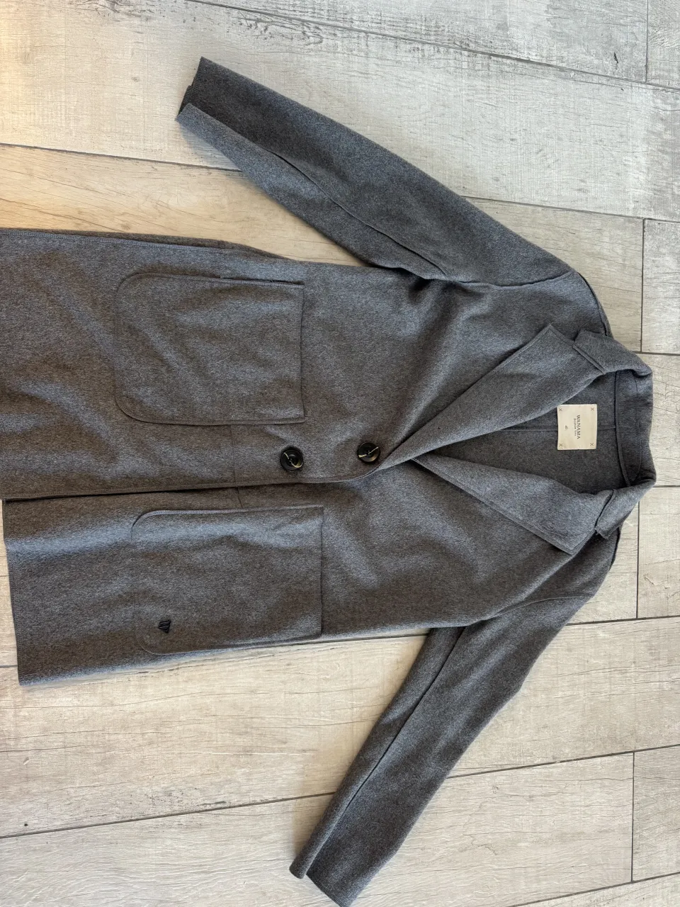 Campera gris de paño con dos botones al frente y bolsillos.