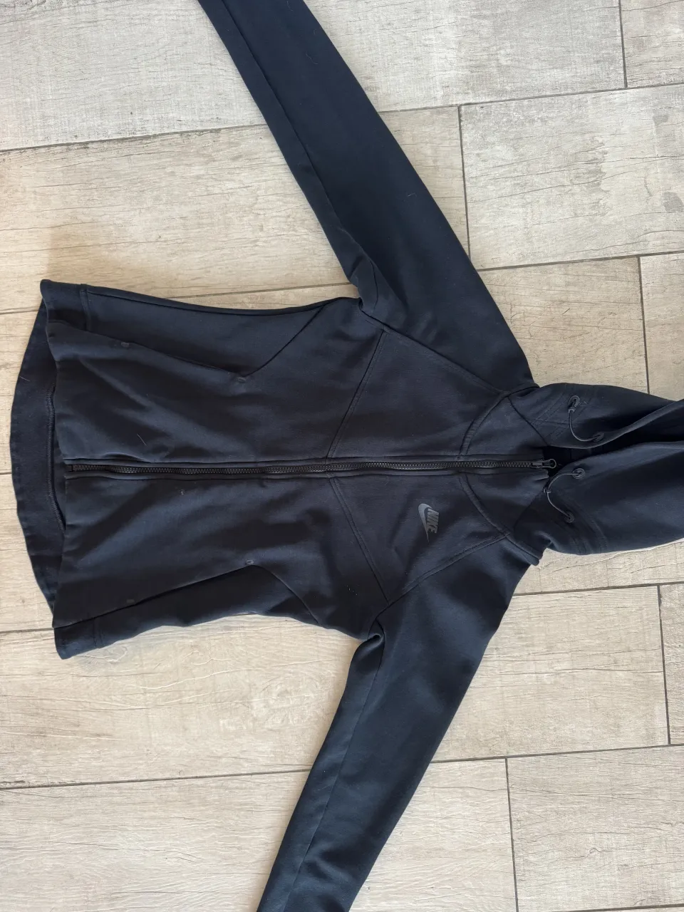 Buzo negro con capucha y cierre completo. Logo de la marca bordado en el frente.