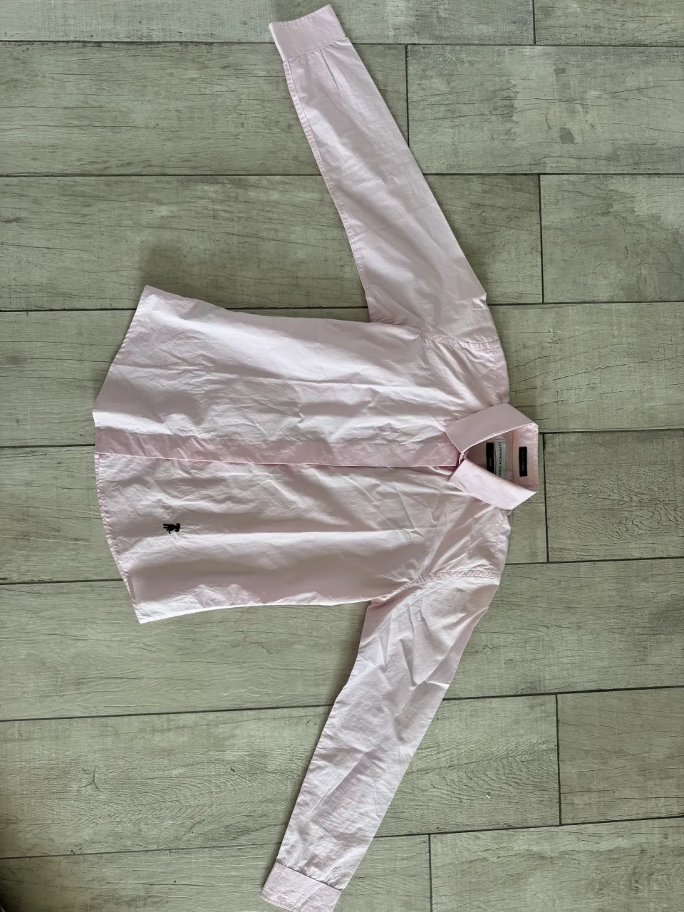 Camisa rosa de manga larga con un pequeño logo bordado en el pecho.