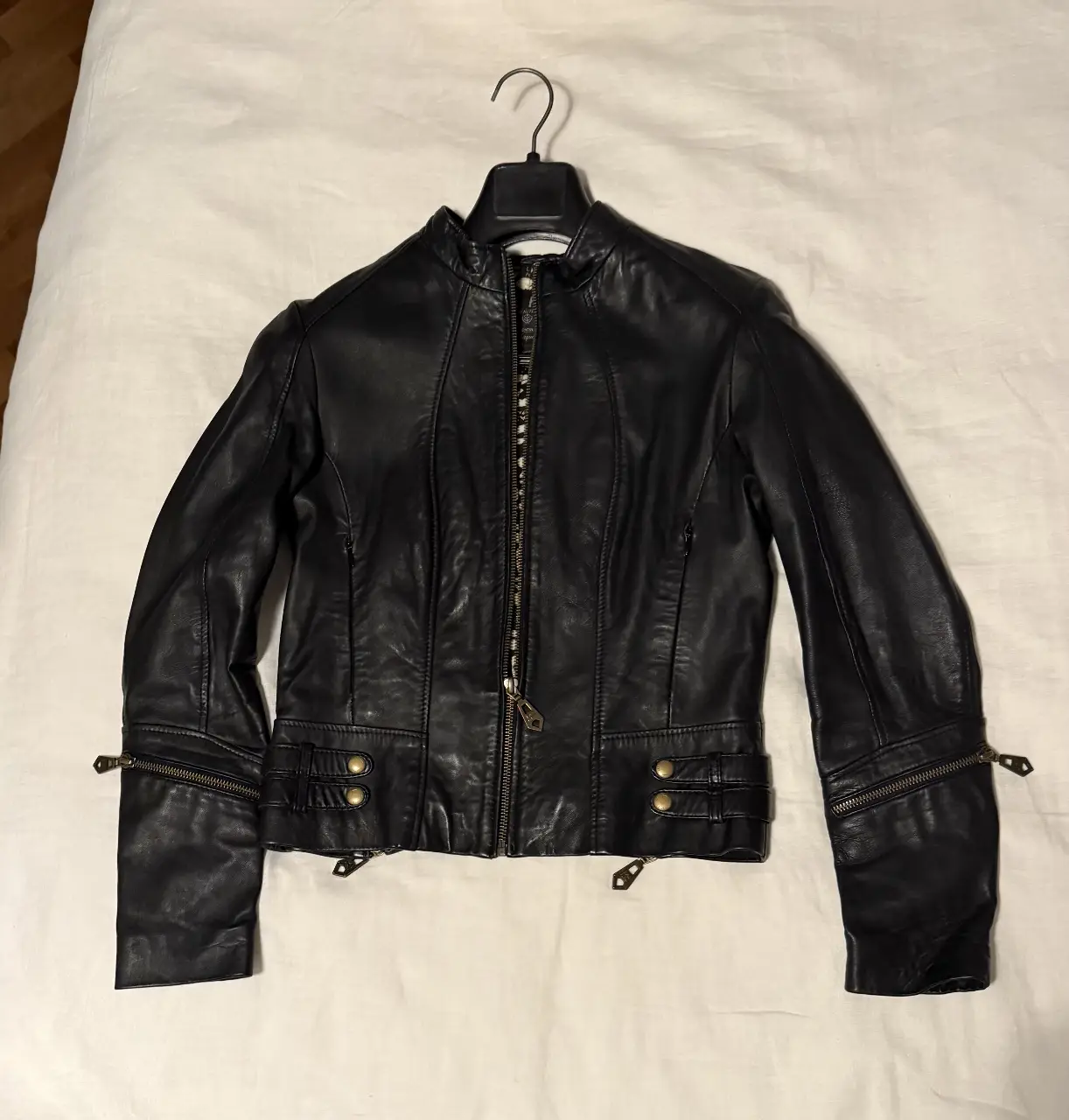 Campera de cuero negra de mujer, estilo biker, con detalles de cierres y botones bronce . Interior con forro estampado. Marca Las Pepas talle 03