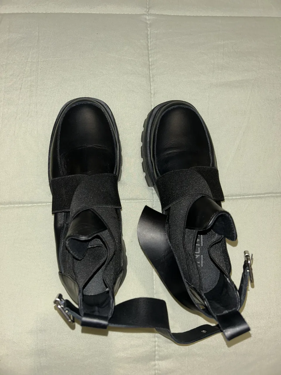 Botines negros de cuero sintético con suela gruesa y detalles de hebilla. Ideales para un look moderno y urbano.