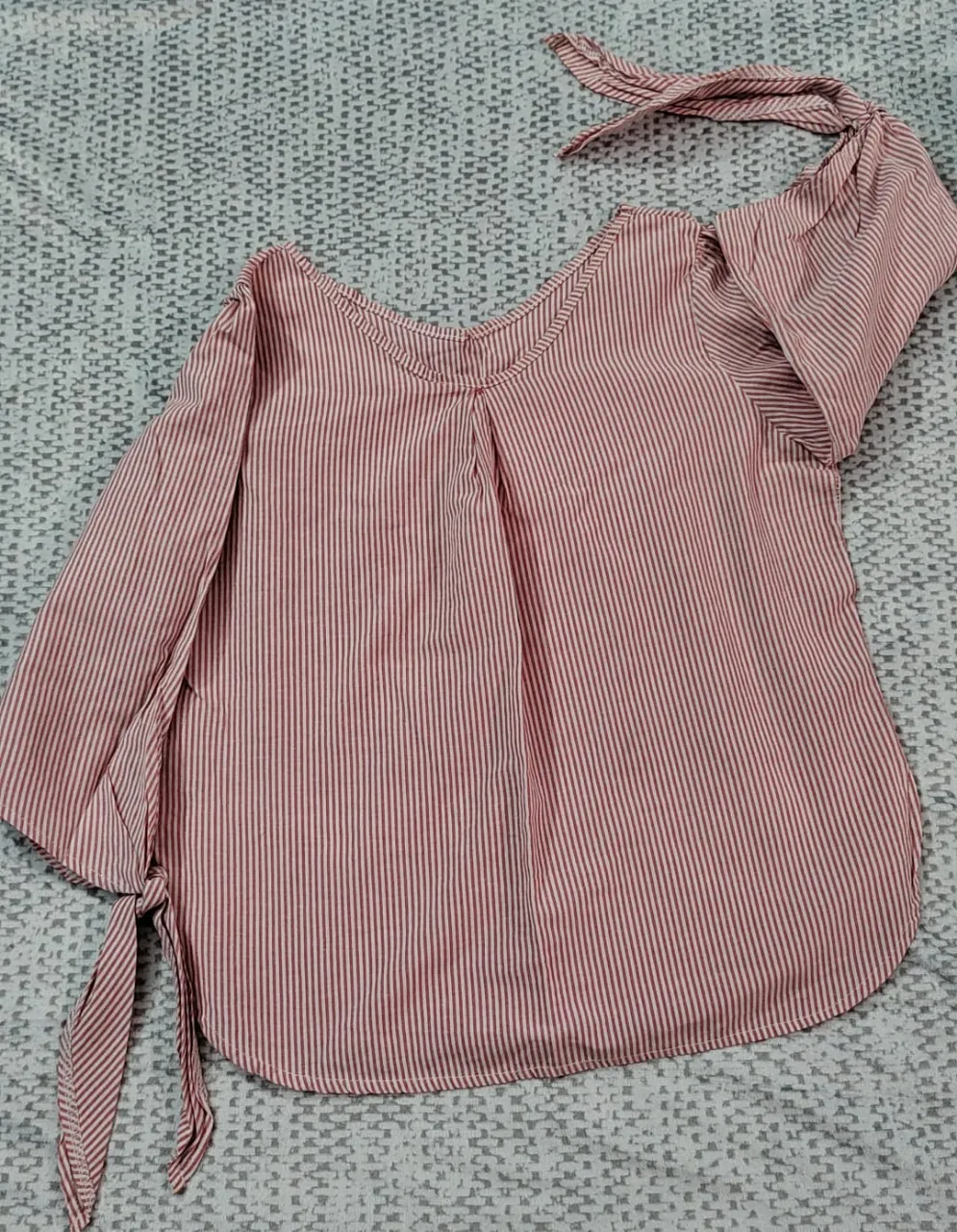 Blusa a rayas rojas y blancas con mangas 3/4 y lazos en los puños y en el cuello. Ideal para un look casual y fresco.