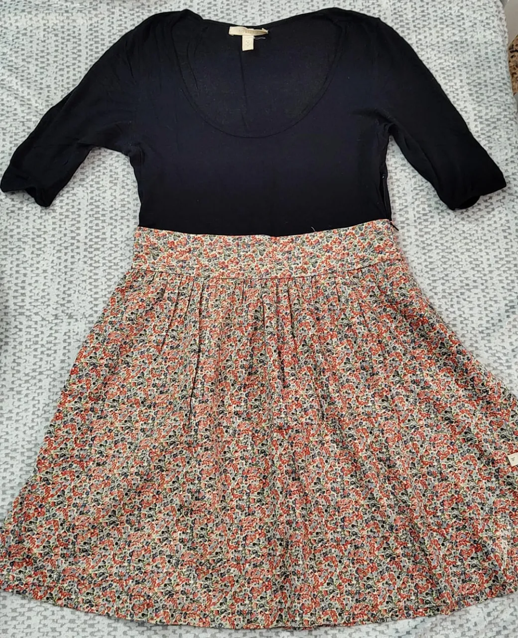 Vestido midi de mujer, con cuerpo negro y falda floreada. Ideal para un look casual y fresco.