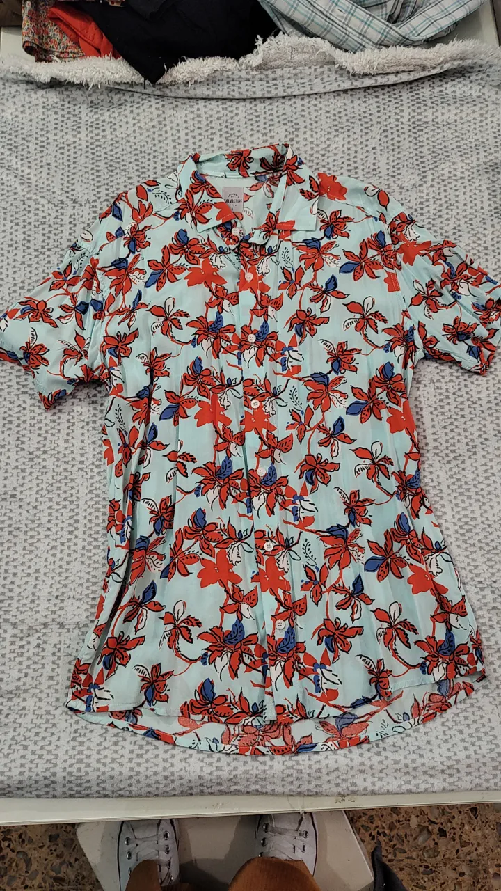 Camisa estampada para hombre, con un diseño floral en tonos celeste, rojo y azul. Ideal para un look casual y fresco.