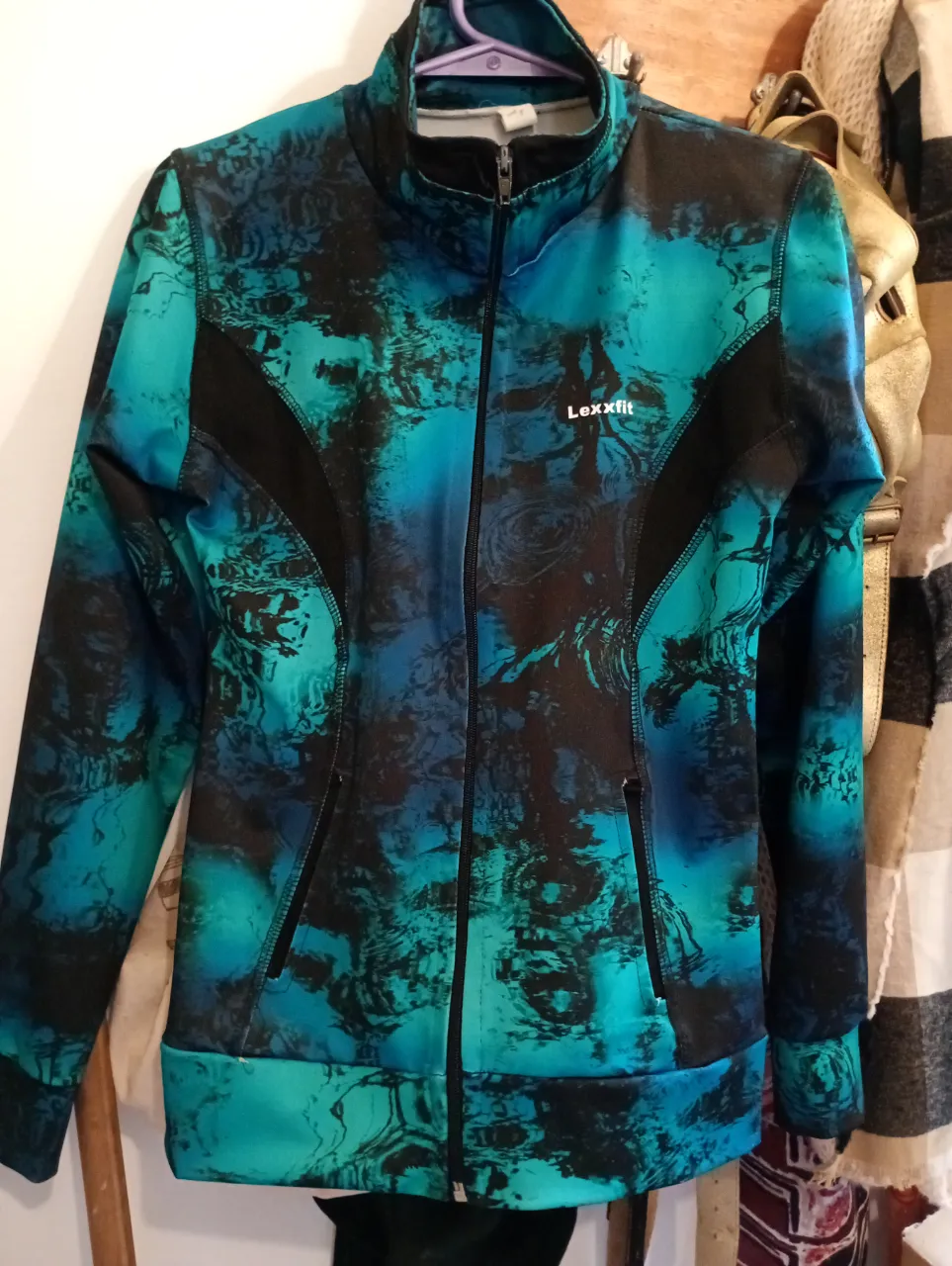 Campera deportiva con cierre completo y cuello alto. Posee bolsillos laterales con cierre. Estampado abstracto en tonos de azul y verde con detalles en negro. Prácticamente sin uso! es elastizada