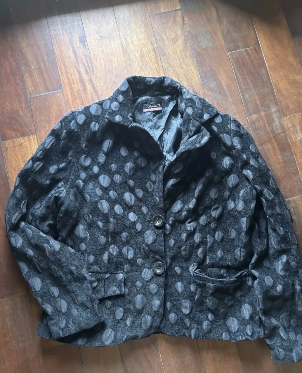 Blazer corto con un estampado de círculos texturizados en relieve. Tiene solapa, dos botones al frente y bolsillos con tapa. Ideal para un look elegante pero con un toque moderno.