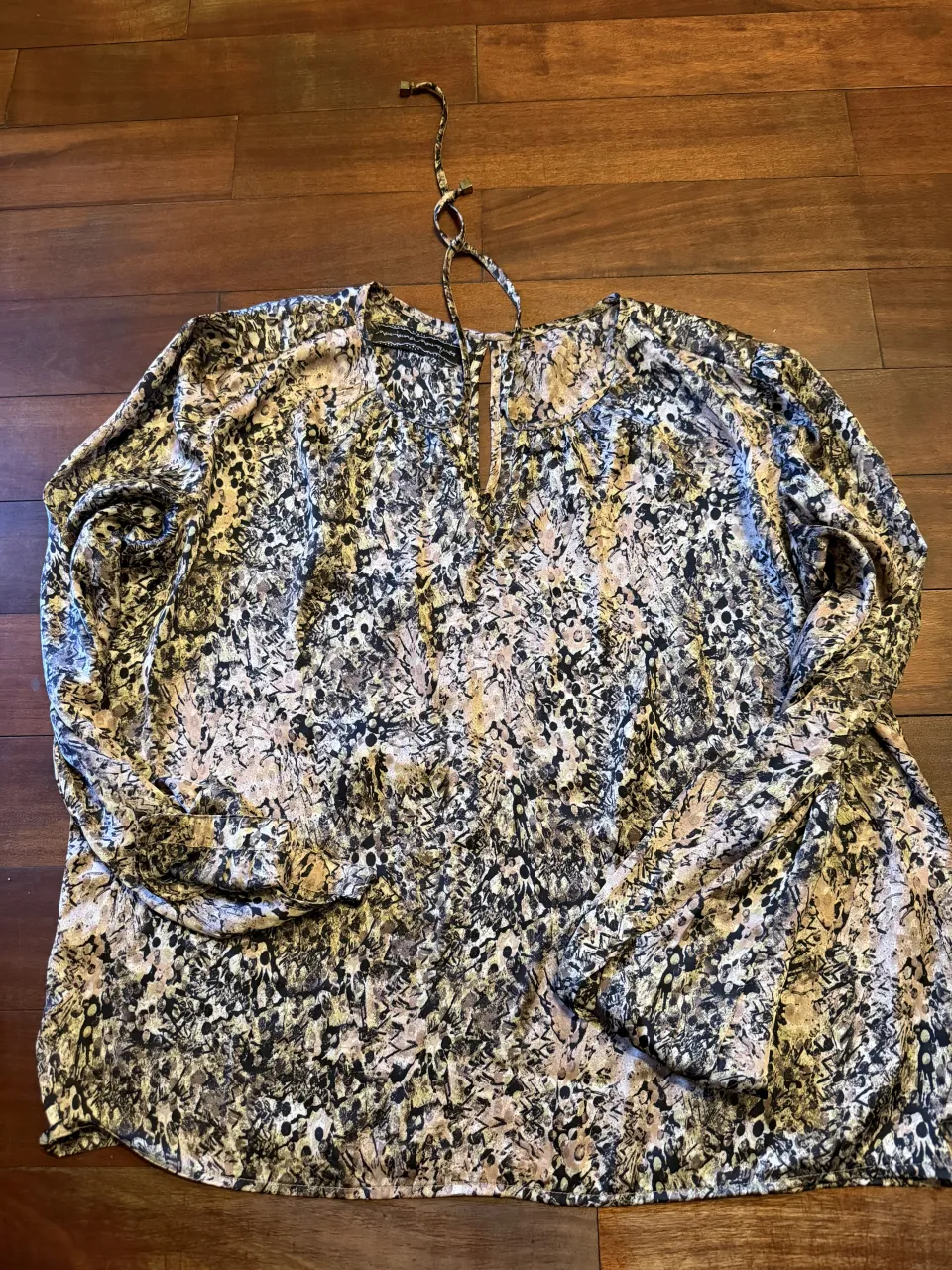 Blusa estampada con mangas largas y escote en V con detalle de lazo. Un diseño único y llamativo, ideal para darle un toque especial a tu look.