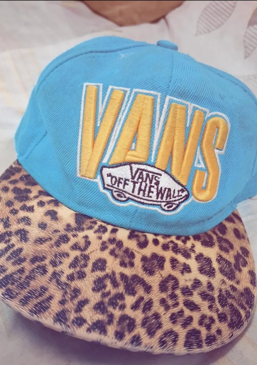 Gorra azul con visera estampada con motivo de leopardo. La visera tiene el logo de Vans bordado.