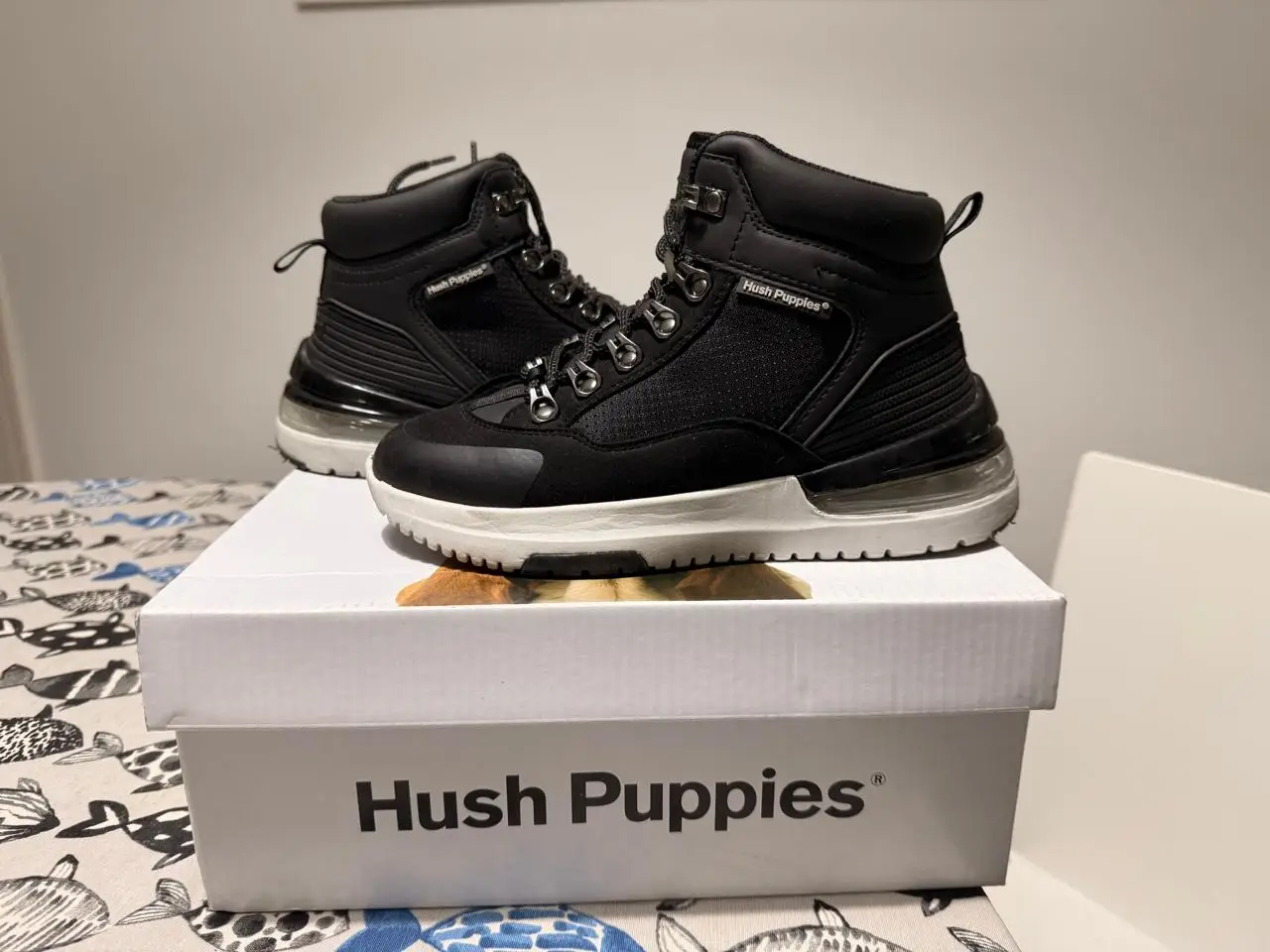 Borcegos Hush Puppies negros de caña alta con cordones y suela blanca. Ideales para un look urbano y cómodo.
