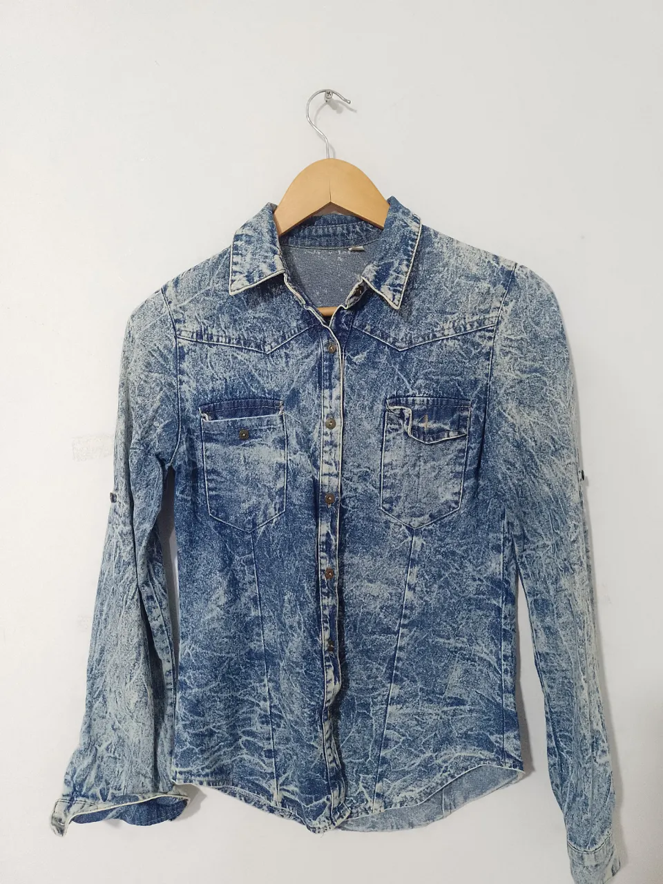 Camisa de jean con efecto gastado, ideal para un look casual y canchero. Con dos bolsillos delanteros y mangas largas que se pueden arremangar. Perfecta para combinar con jeans o pantalones de vestir.