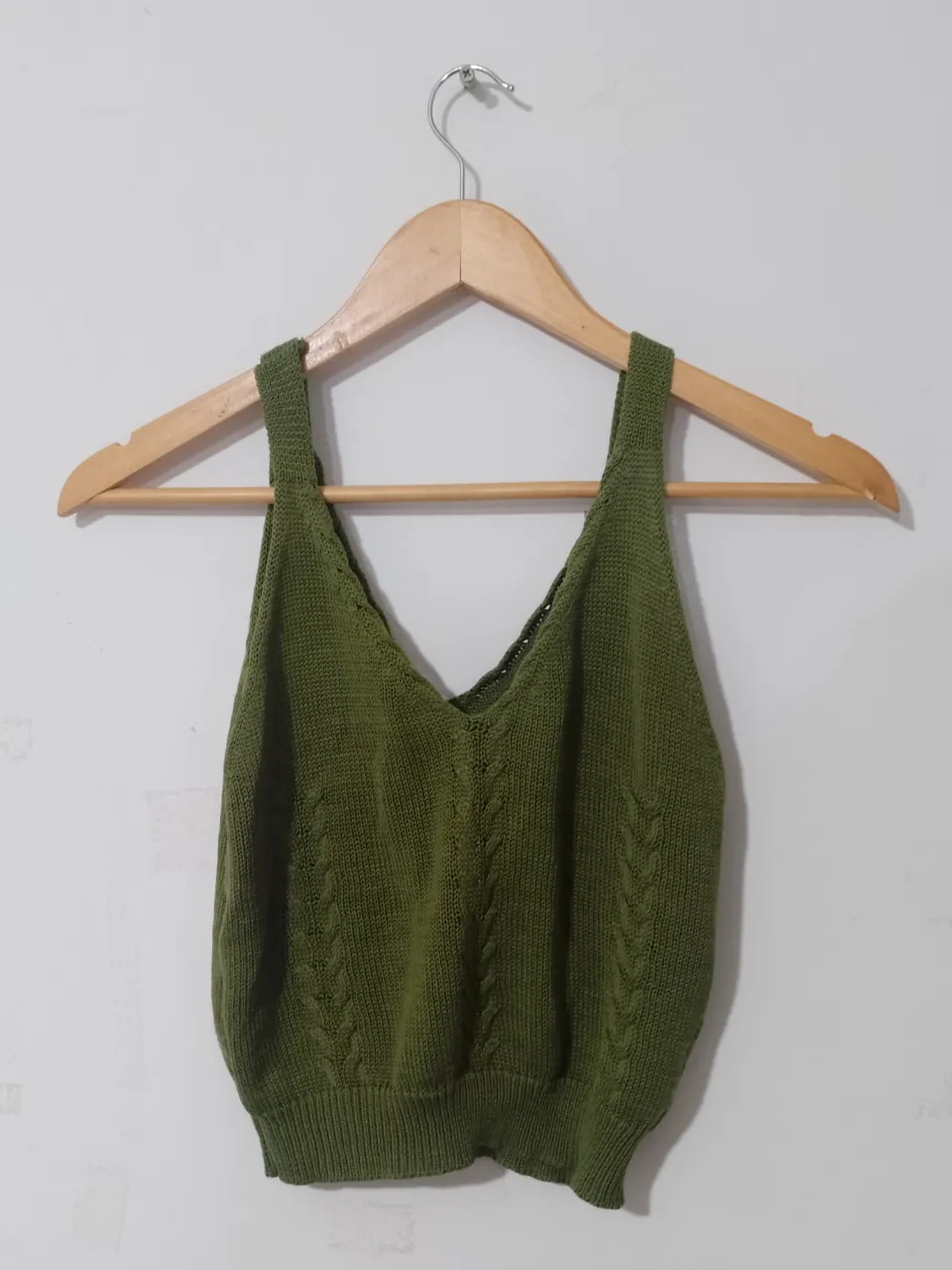 Top tejido de punto en color verde oliva, con diseño de trenzas en el frente y escote en V. Ideal para un look casual y fresco.