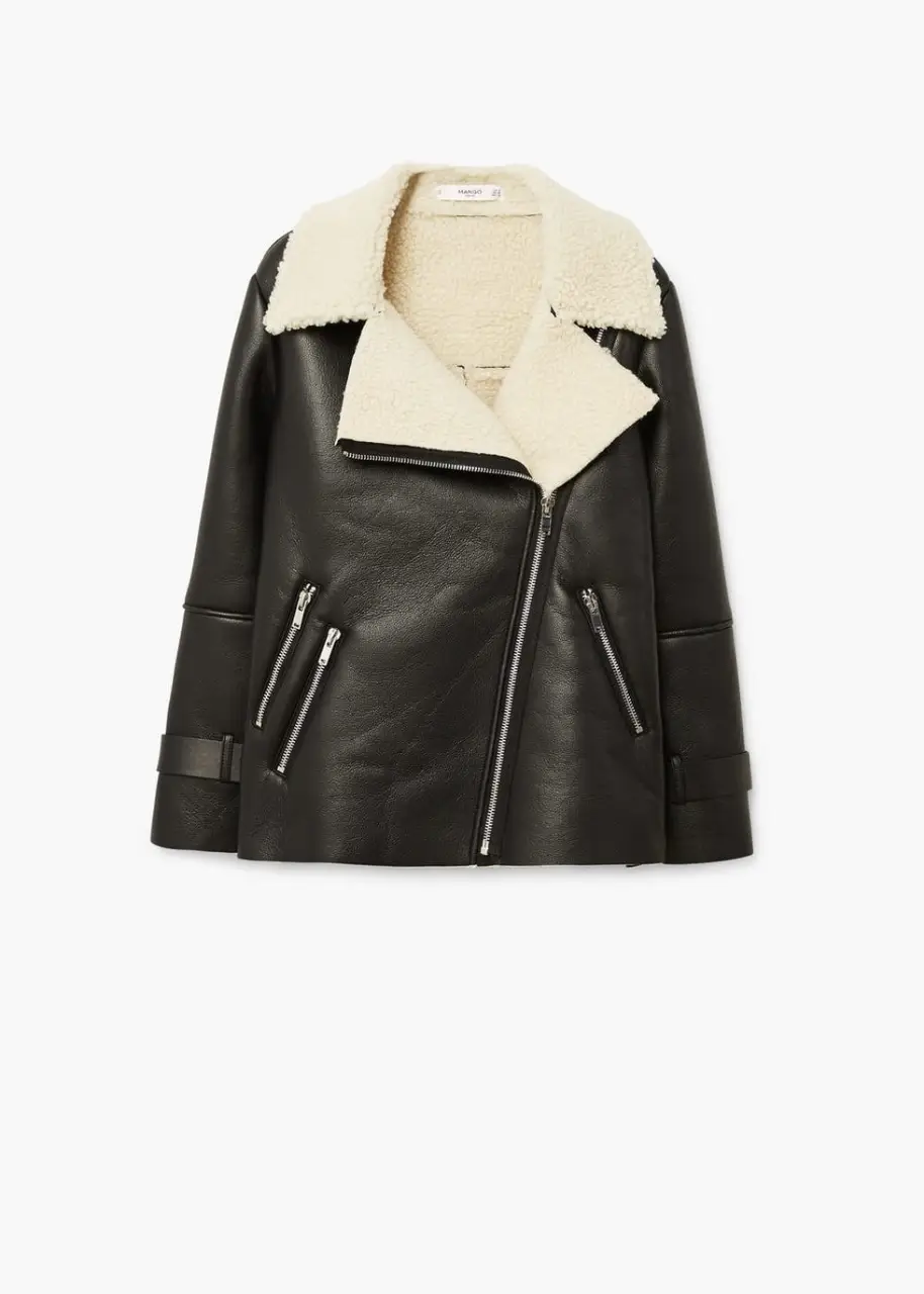 Campera biker de cuero sintético negro con cuello y forro de piel sintética color crudo. Detalles de cierres metálicos y cinturón en la cintura. Ideal para un look moderno y abrigado.