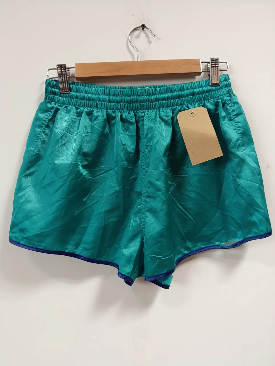 Shorts deportivos de color verde turquesa, con cintura elastizada y detalles en azul marino en los bordes. Ideales para entrenar o para un look casual y cómodo.