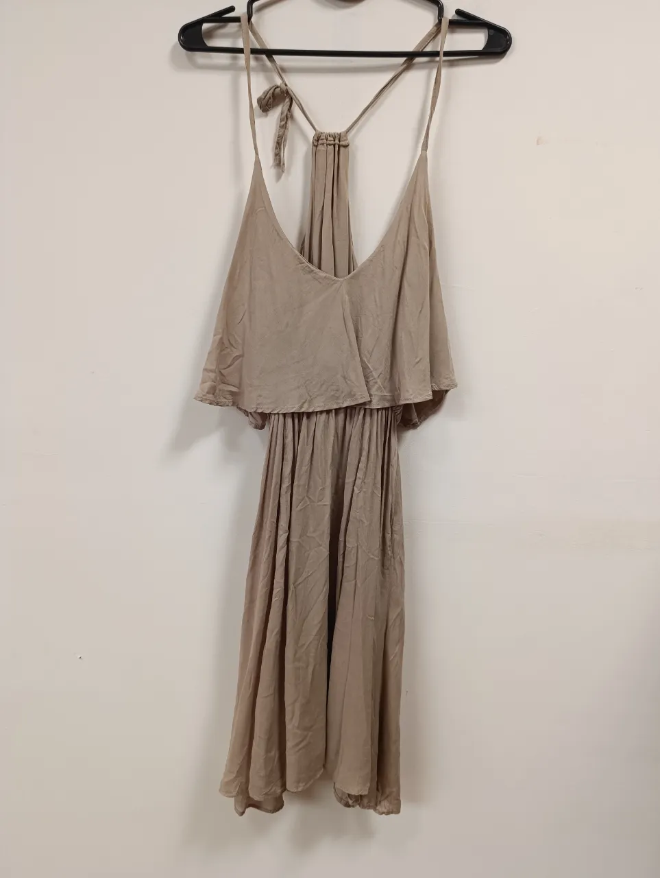 Vestido largo de gasa color tiza, con breteles finos y escote en V. Posee un detalle de volado en la parte superior y la falda es suelta y con movimiento. Ideal para un look boho chic o para usar en un día de playa o festival.