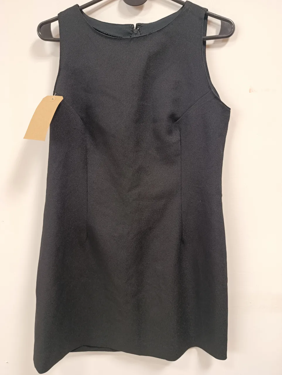 Vestido negro corto, sin mangas y con cuello redondo. Ideal para un look elegante y sofisticado.