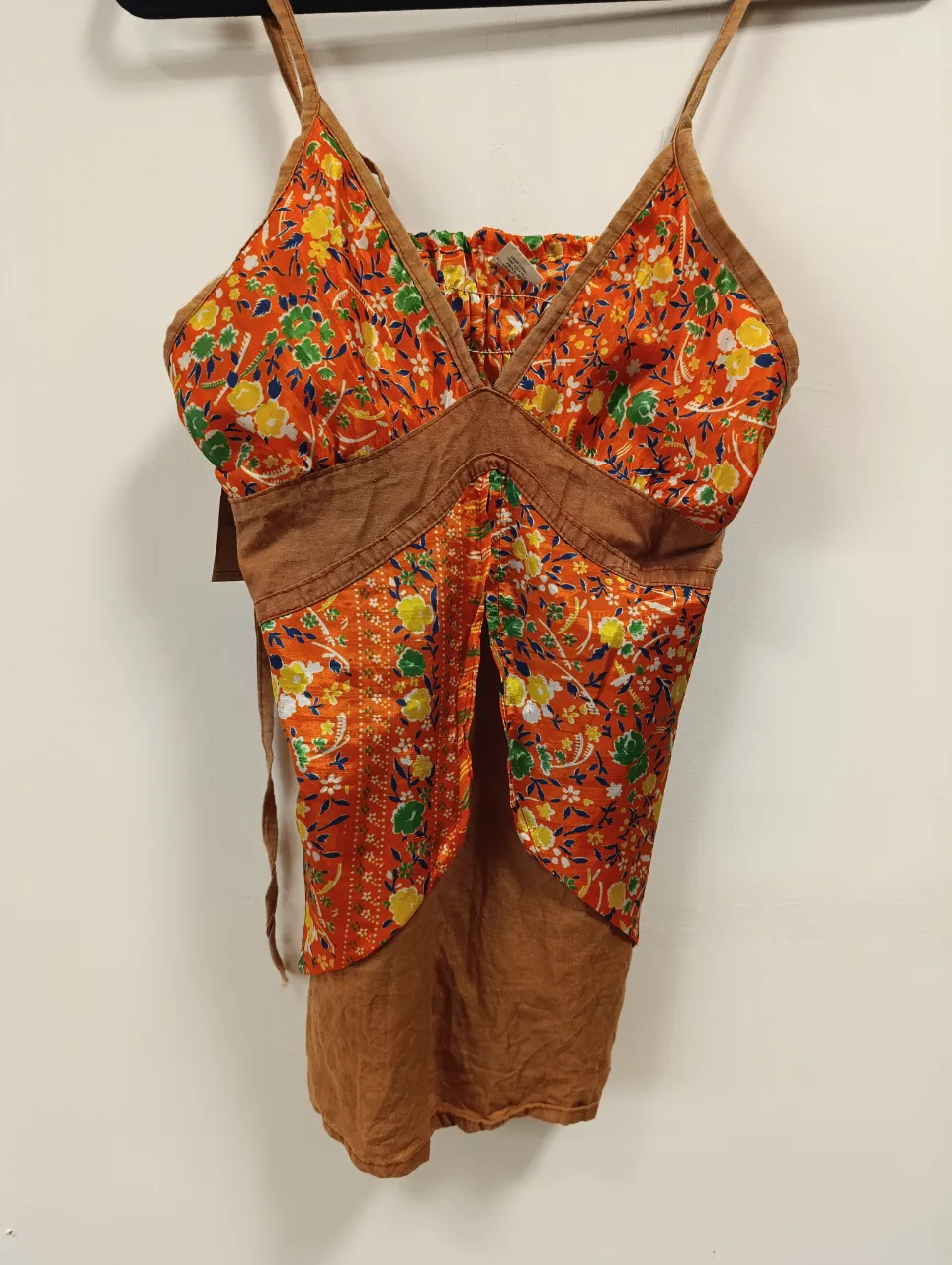 Top estampado floral vibrante con tiras finas y detalles de tela rústica. Un diseño único y fresco, perfecto para un look de verano con un toque bohemio.