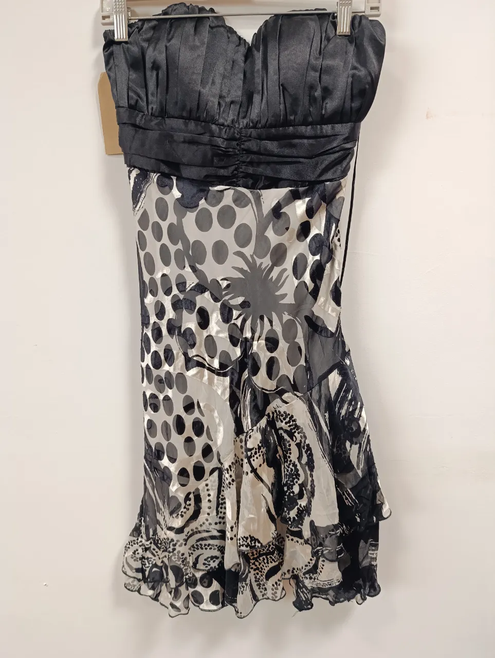 Vestido strapless con estampado abstracto en blanco y negro. Posee un corpiño fruncido y una falda con volados, ideal para una salida nocturna o una fiesta.