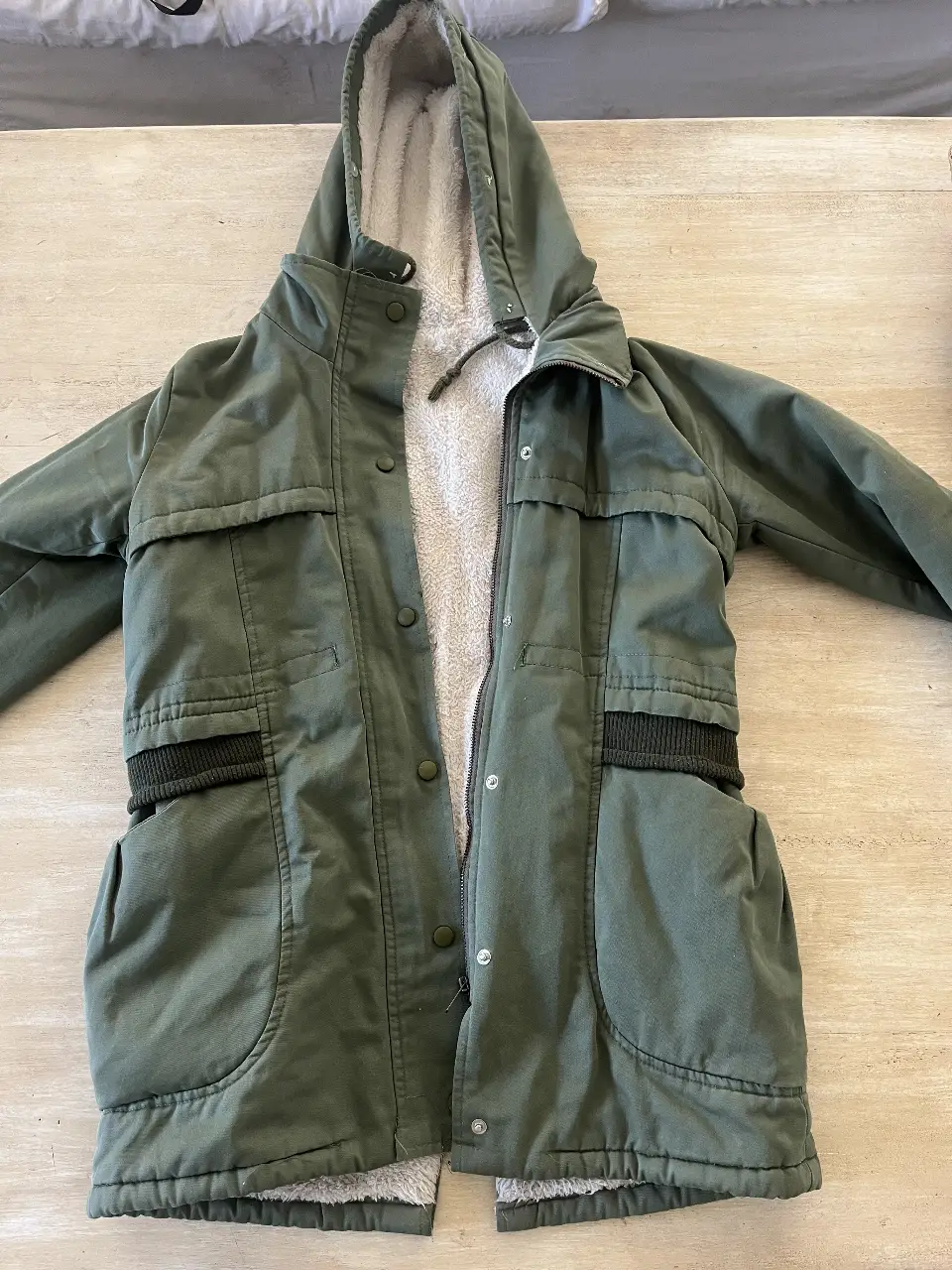 Campera parka verde con capucha y forro de piel. Ideal para el invierno, con bolsillos amplios 