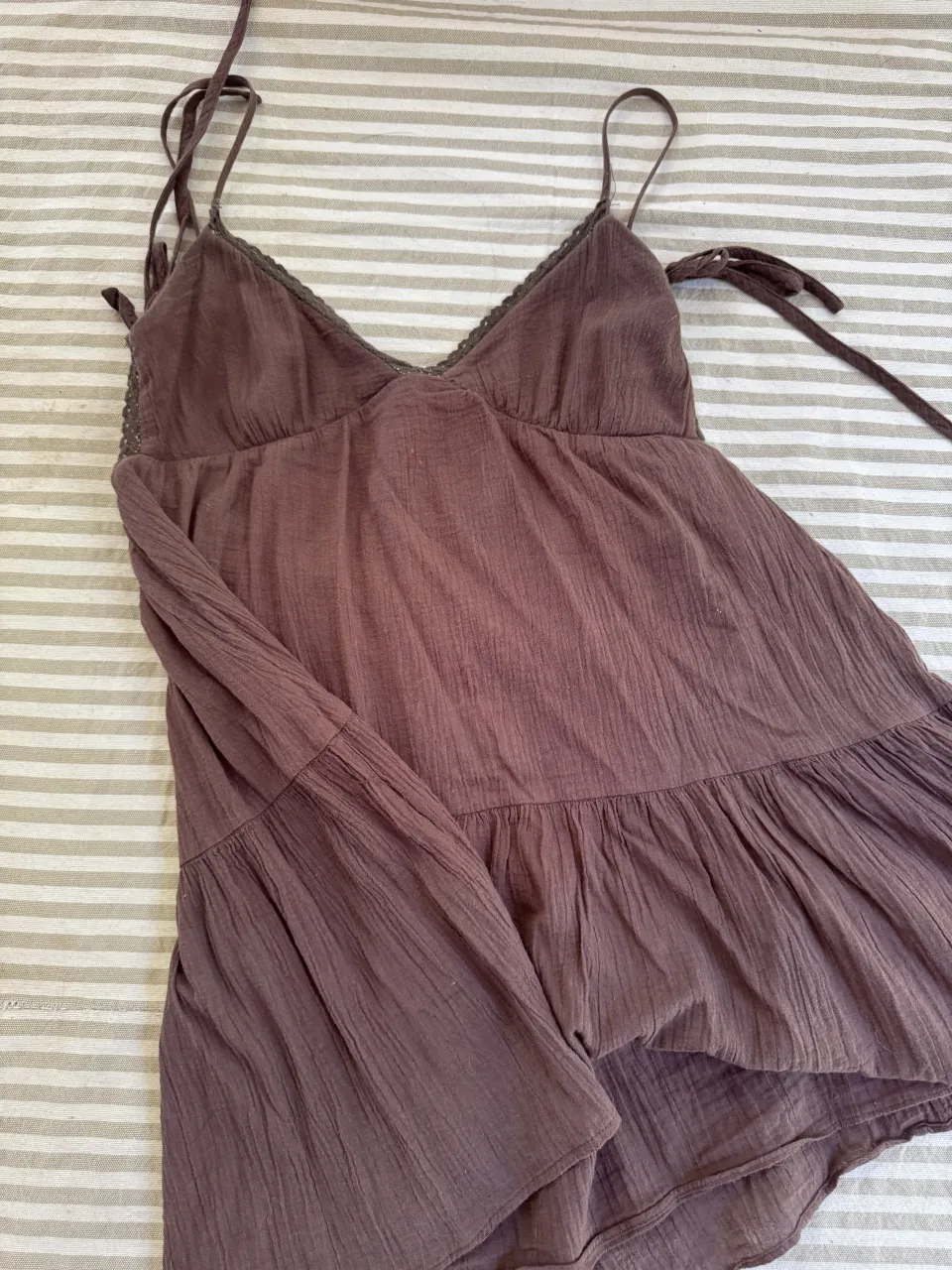 Vestido corto de morley con tiras finas y detalles de puntilla en el escote. Posee volado en la parte inferior.