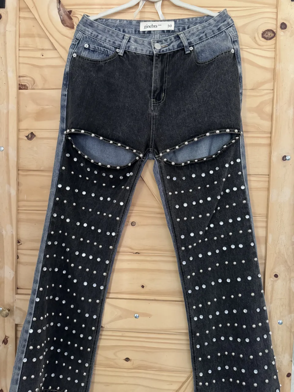 Jeanscon roturas y tachas plateadas. Diseño de dos tonos, con la parte superior en denim claro y la inferior en denim oscuro. Detalle de tachas y apliques plateados en las roturas y a lo largo de las piernas.