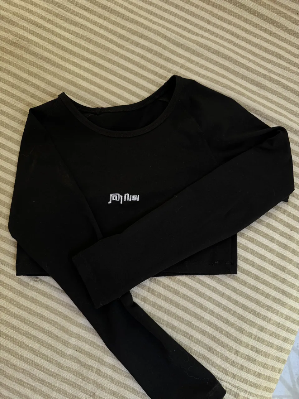 Remera negra manga larga, crop top, con logo blanco en el frente.