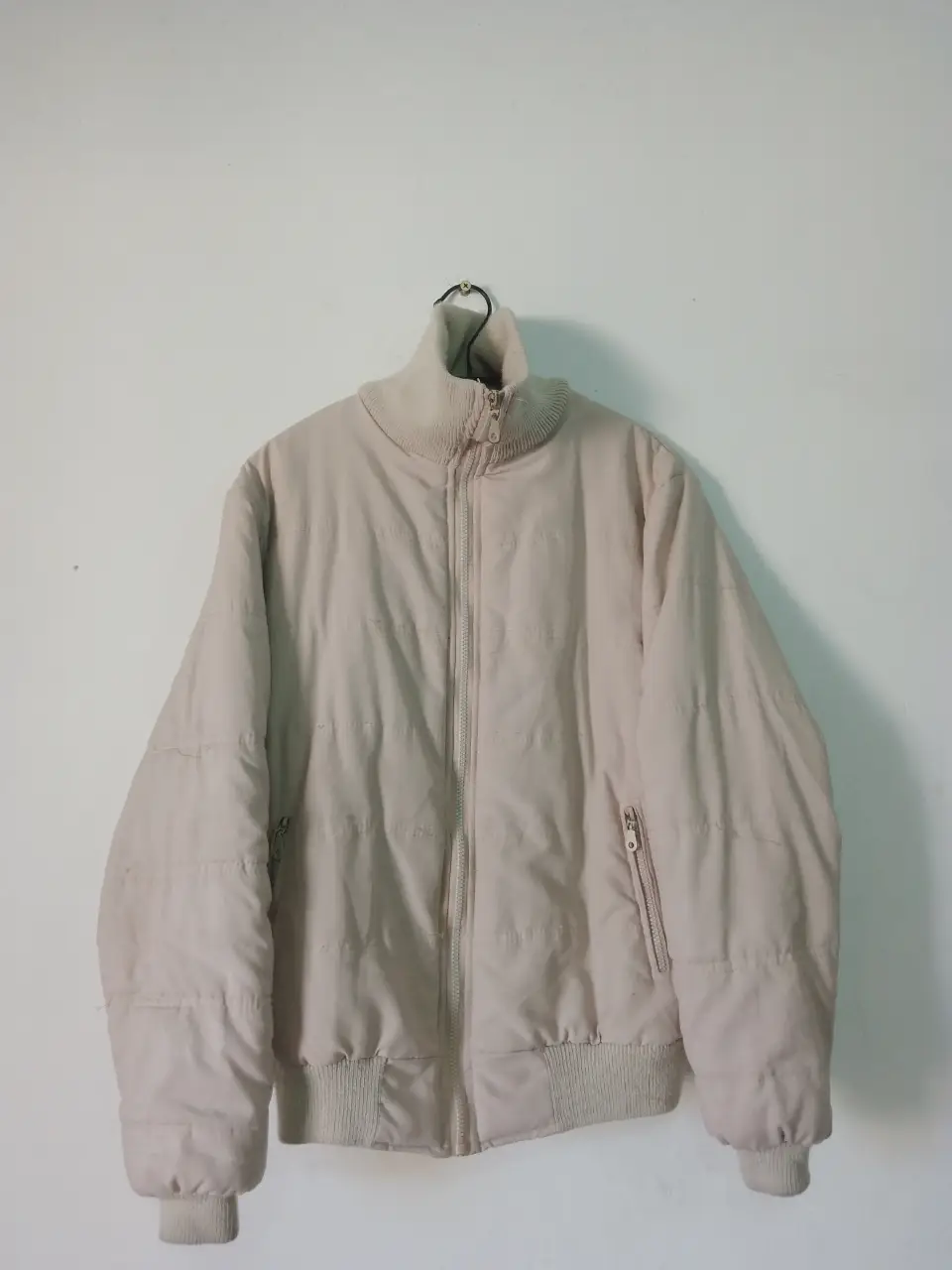 Campera bomber beige, ideal para el invierno. Con cierre frontal y bolsillos laterales. Cuello alto y puños elastizados.
